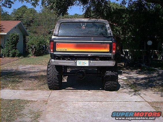 Rear view of lifted Ford Bronco with orange and yellow stripe on tailgate. License plate reads 033 PVG