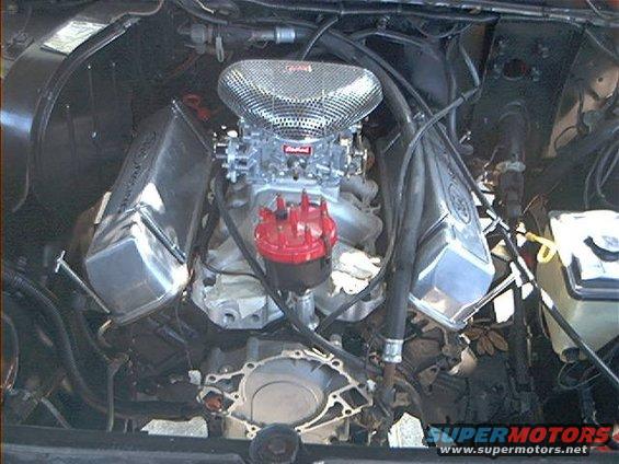 Engine bay with chrome valve covers, a Holley carburetor, and a red distributor cap