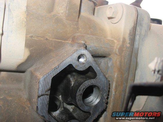Close-up of a metal engine component with bolt holes