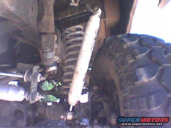 close-up of a vehicle's front suspension with coil spring and shock absorber