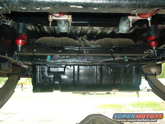 Underside view of a vehicle showing fuel tank, leaf springs, and exhaust components