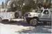 1990 Ford Bronco - A lifted white Ford Bronco is hitched to a white utility trailer in a driveway.