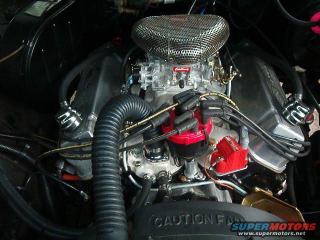 Close-up of a V8 engine with a chrome air cleaner, red distributor cap, and Holley carburetor