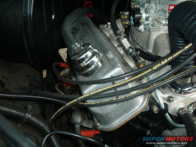 close-up of engine components, including valve cover, spark plug wires, and carburetor