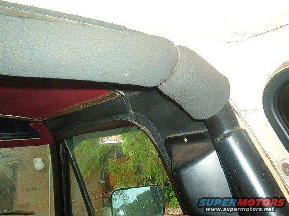 Interior shot of a vehicle's upper door frame and headliner. A side mirror is visible