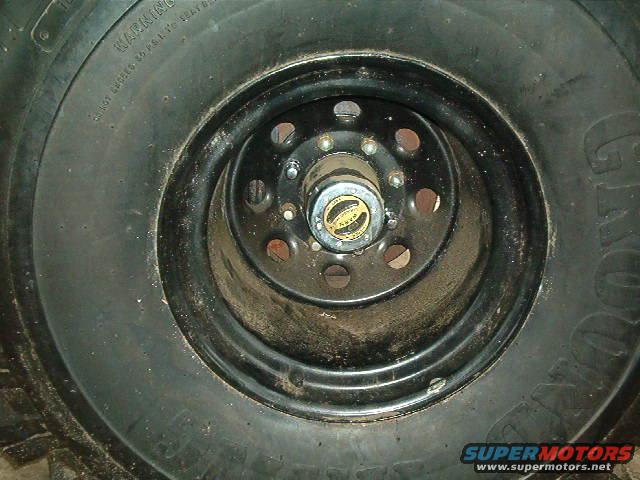 Close-up of a wheel hub with a yellow and black decal, surrounded by a black rim and tire tread