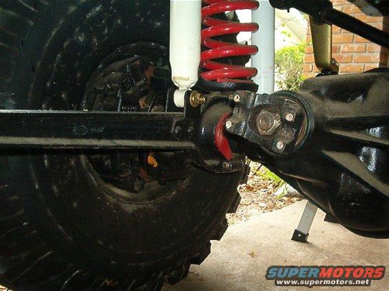 Close-up of a vehicle's rear axle, shock absorber, and coil spring