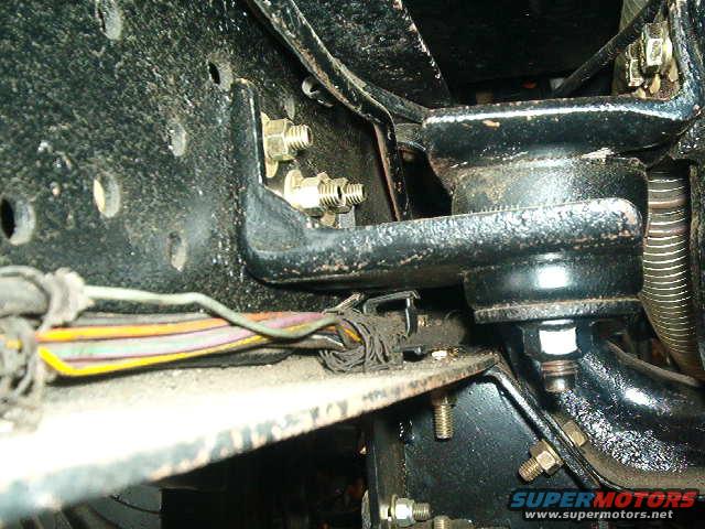 Close-up of black metal brackets and wiring harness on a vehicle chassis