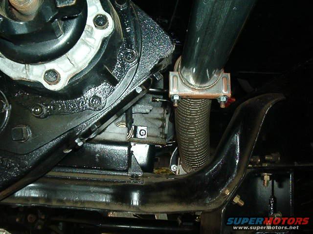 Close-up of exhaust pipe and engine components, including a U-clamp and flexible exhaust section