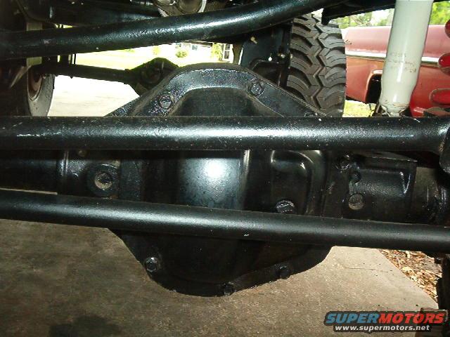 Rear differential and suspension of a vehicle, with a red vehicle visible in the background