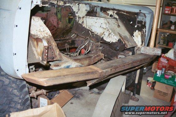 rusted vehicle chassis with front end removed, showing frame and engine bay components
