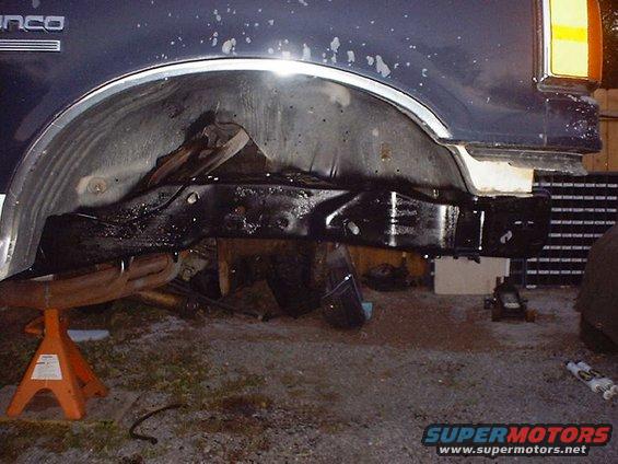 Close-up of a 1988 Ford Bronco's frame and suspension components, supported by jack stands
