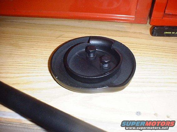 Black metal part with two bolts on wooden surface