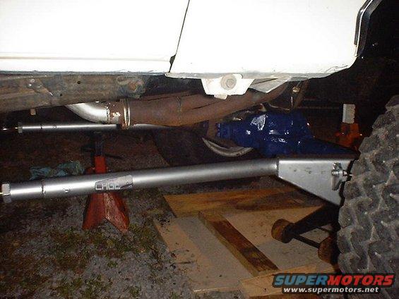 Silver suspension arm with 'CHGE' visible, under white vehicle body