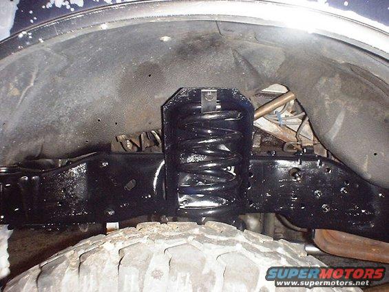 Close-up of a vehicle's front axle and coil spring assembly