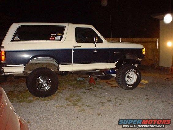 1988 Ford Bronco lifted with Big Foot tires, two-tone paint, and stickers on the rear window