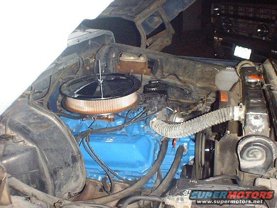 Engine bay showing a blue engine block, air filter, radiator, and hoses