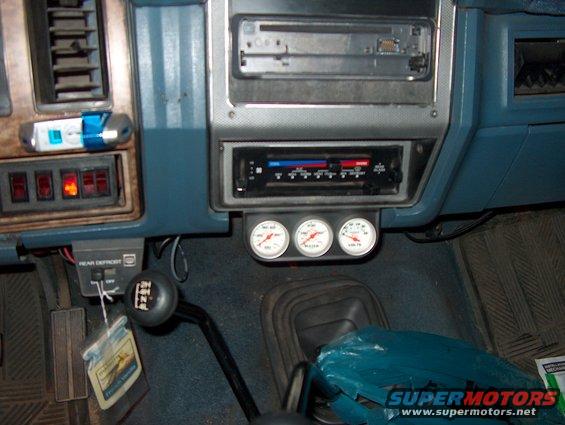 Dashboard interior with three gauges, a shifter, and a car stereo