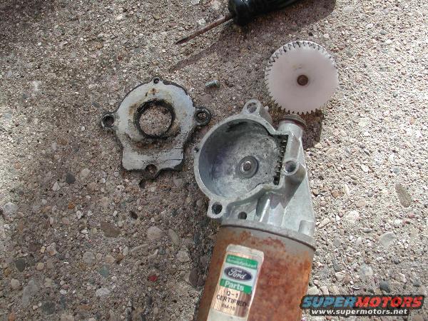 Disassembled window motor with Ford parts label and plastic gear