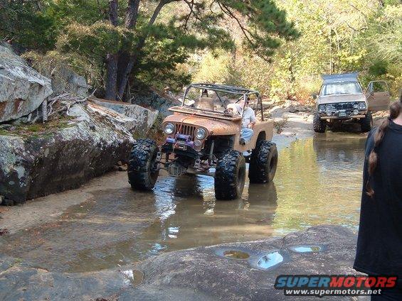 Two off-road vehicles navigating a rocky stream bed