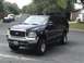 2003 Ford Excursion - A black Ford Excursion SUV is parked on a residential street with other vehicles in the background.
