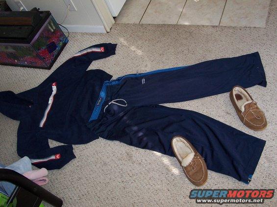 Navy blue sweatsuit and two brown moccasin slippers laid out on a carpeted floor