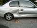 2001 Hyundai Accent - This 2001 Hyundai Accent coupe shows extensive damage to its rear quarter panel and door, indicating a significant impact.