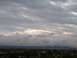 1990 Ford Bronco - A dramatic sky filled with heavy clouds looms over a distant city skyline.