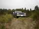 1983 Ford Ranger - A dark blue 1983 Ford Ranger pickup truck navigates a dirt path surrounded by vegetation under an overcast sky.