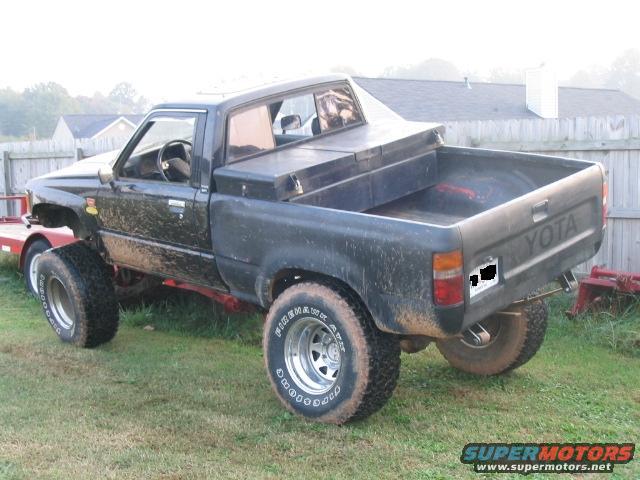 Black Toyota pickup truck with a toolbox in the bed, parked on grass