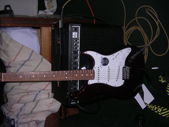 Electric guitar with white pickguard and dark body connected to an amplifier