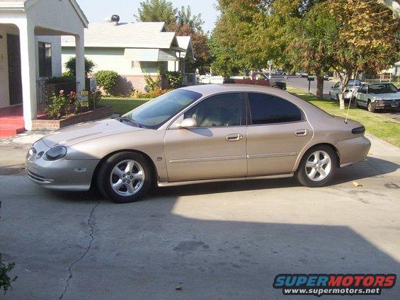1998 Mercury Sable sedan parked on a cracked concrete driveway, side view