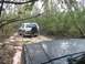 1988 Ford Bronco - Two vehicles navigating a wooded trail; the rear of a 1988 Ford Bronco is visible.