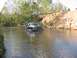 1988 Ford Bronco - A person attempts to push a white and black SUV that is stuck in a shallow river.