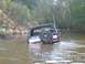 1988 Ford Bronco - This 1988 Ford Bronco is partially submerged in a body of water, with trees and a bank in the background.