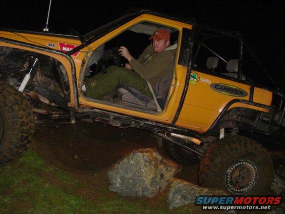 Yellow off-road SUV with large tires, driver inside, navigating rocks at night