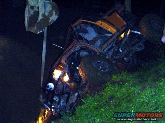Overturned orange off-road vehicle on its side with large tires