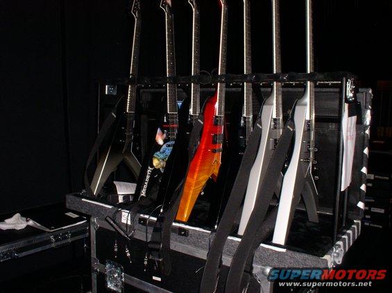 Several electric guitars in a black case, some with V-shaped bodies and flame-like finishes