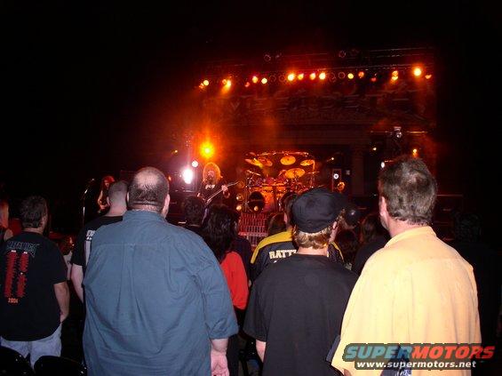 Crowd watches a band perform on a stage with bright lights