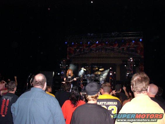 Concert crowd watches band perform on stage with "MEGADETH" banner