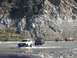 1992 Ford Bronco - A convoy of off-road vehicles navigates a riverbed, with the lead vehicle appearing to be a 1992 Ford Bronco.