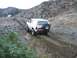 1992 Ford Bronco - A white Ford Bronco navigates a challenging off-road path with steep, rocky hillsides.