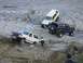 1992 Ford Bronco - Multiple SUVs are shown off-roading in a rocky, dry riverbed with people observing.