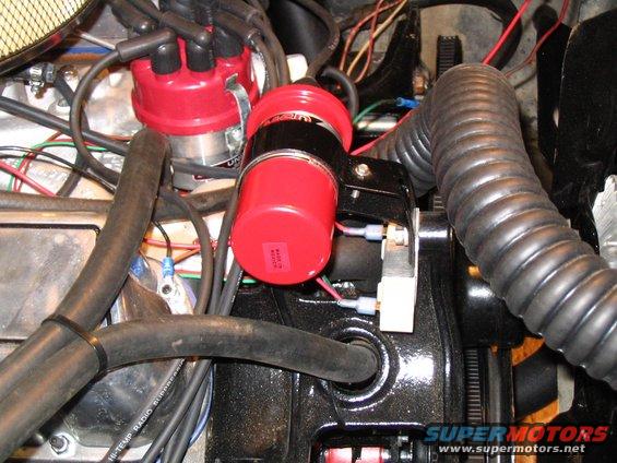 Engine bay with red ignition coil, distributor cap, and black hoses