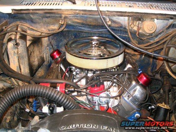 Engine bay showing V8 engine, air cleaner, distributor, and hoses. 'CAUTION FAN' text visible