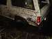 1989 Ford Bronco - This white SUV, heavily caked in mud, appears to be stuck in a dark, wet environment.