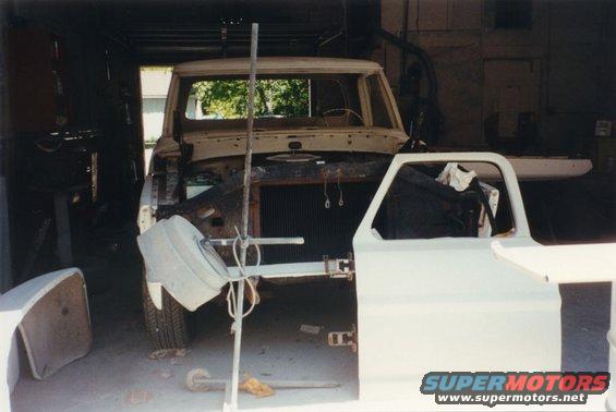 1968 Ford F-100 truck body in a workshop, disassembled with doors removed