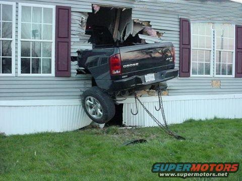 Black Dodge Ram truck crashed through house side, rear view