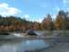 1987 Ford Bronco - A red SUV navigates a muddy off-road course during autumn.