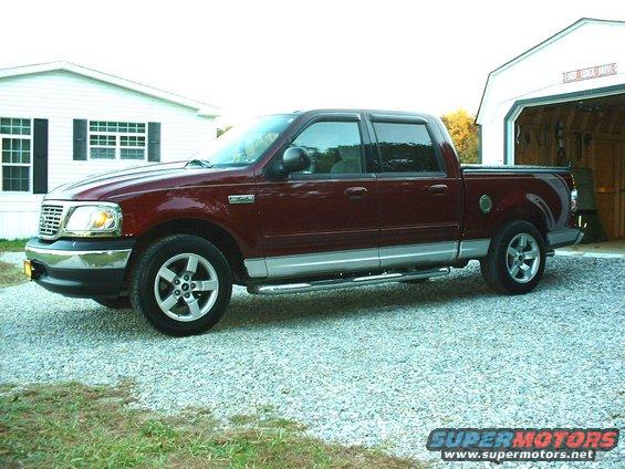 Maroon four-door pickup truck parked in gravel driveway